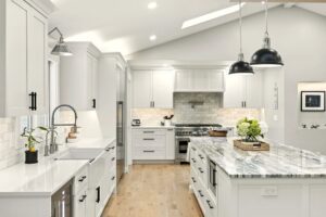 Bright modern kitchen with white cabinets and marble countertops.