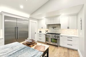 Bright modern kitchen with white cabinetry and stainless steel appliances.