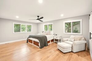Spacious, bright bedroom with large windows and wooden flooring.
