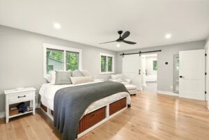 Bright modern bedroom with large bed and wooden floor.