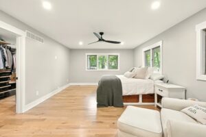 Bright, minimalist bedroom with wooden floors and modern ceiling fan.
