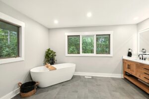 Modern bathroom with a freestanding tub and large window.