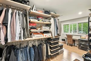 Organized walk-in closet with clothes, shelves, and storage bins.