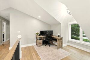Minimalist home office with wooden desk and computer setup near window.