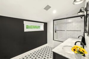 Modern bathroom with black and white design and glass shower enclosure.