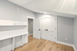 Minimalist room with white walls, built-in shelves, and a double-door closet.