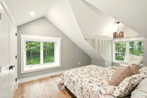 Bright attic bedroom with sloped ceilings and a floral bedspread.
