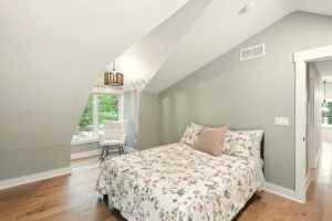 Bright bedroom with floral bedding and a cozy reading nook by the window.