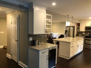 Modern kitchen with white cabinets and island, featuring stainless steel appliances.