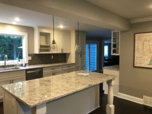 Modern kitchen with granite island and pendant lights.