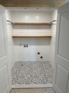 Laundry room with patterned tile floor and wooden shelves.