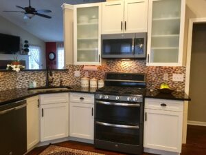 Modern kitchen with black appliances and white cabinets.