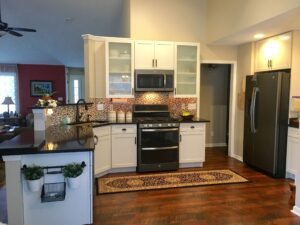 Cozy kitchen with white cabinets, stainless appliances, and wooden floors.