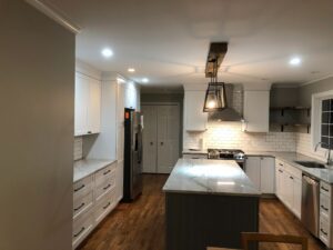 Modern kitchen with white cabinets and a central island under recessed lighting.