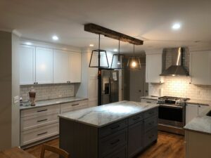 Modern kitchen with marble island and pendant lights.