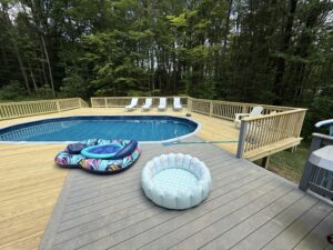 Two inflatable pools on a wooden deck next to a swimming pool.