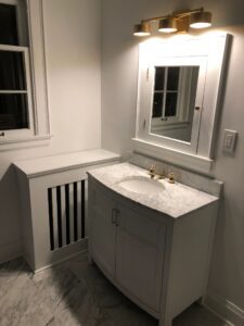 Modern white bathroom vanity with marble countertop and mirror.