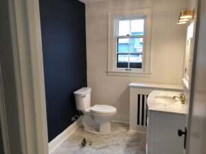 Modern bathroom with navy accent wall and marble flooring.