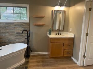 Modern bathroom with freestanding tub and wooden vanity under warm lighting.
