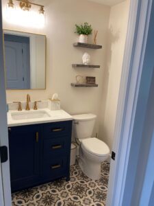 Modern bathroom with navy vanity and patterned floor tiles.