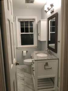 Small bathroom with white decor and marble flooring.
