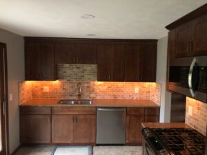 Modern kitchen with dark wood cabinets and warm under-cabinet lighting.