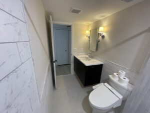Modern bathroom with white and gray tones, featuring a vanity and toilet.