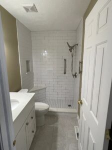Modern bathroom with white tiles, vanity, and toilet.