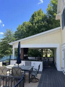 Outdoor patio with seating and a lake view under a sunny sky.