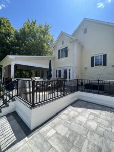 Elegant white two-story house with a spacious patio and black railing.