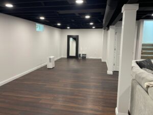 Empty room with dark wooden floor and white walls under ceiling lights.