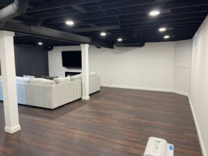 Modern living room with white sofas and dark wooden floor.