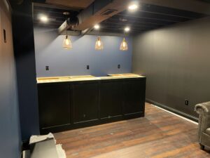 Newly installed dark cabinetry and lighting in a modern basement bar area.