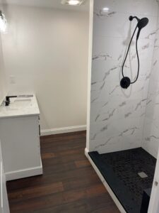 Modern bathroom shower with marble tiles and dark floor base.