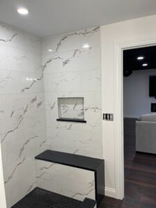 Modern shower with marble walls and built-in bench.