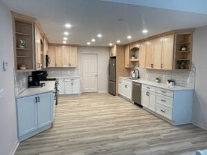 Spacious modern kitchen with light wood cabinets and stainless steel appliances.