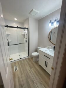 Modern bathroom with glass shower doors and wood flooring.
