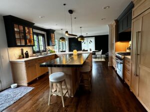 Modern kitchen with an island and wooden stools under warm lighting.