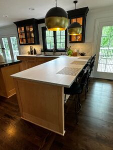Modern kitchen island with white countertop and black bar stools.