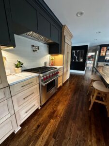 Modern kitchen with marble countertops and dark wood flooring.