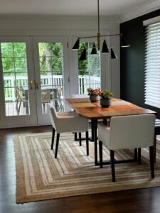 Modern dining area with wooden table and white chairs by large glass doors.