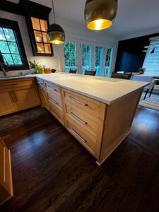 Modern kitchen island with wooden cabinets and light countertop.